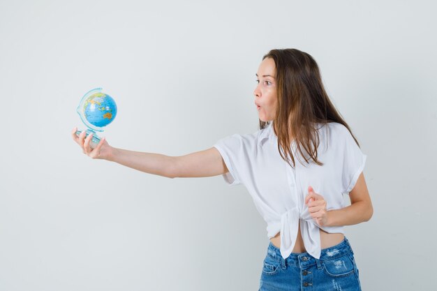 Mooie dame in witte blouse die bol aan iemand geeft en gericht, vooraanzicht kijkt.