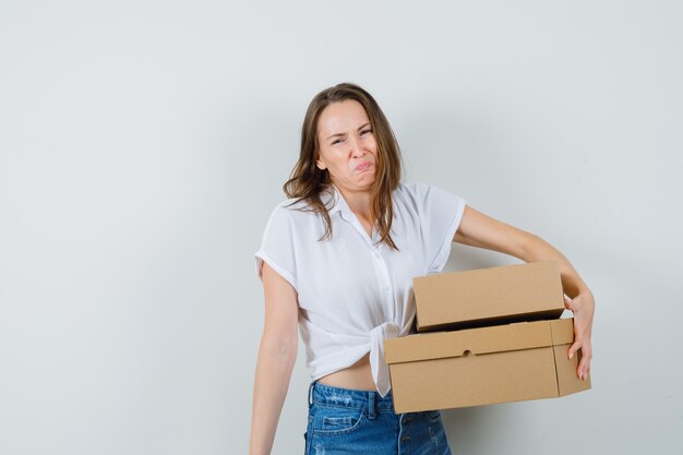 Mooie dame in witte blouse met dozen en op zoek irriterend, vooraanzicht.