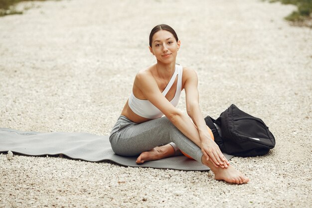 Mooie dame training op een zomerstrand. Brunette doet yoga. Meisje in een sportpak.