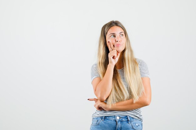 Mooie dame wegkijken in t-shirt en peinzend, vooraanzicht kijken.