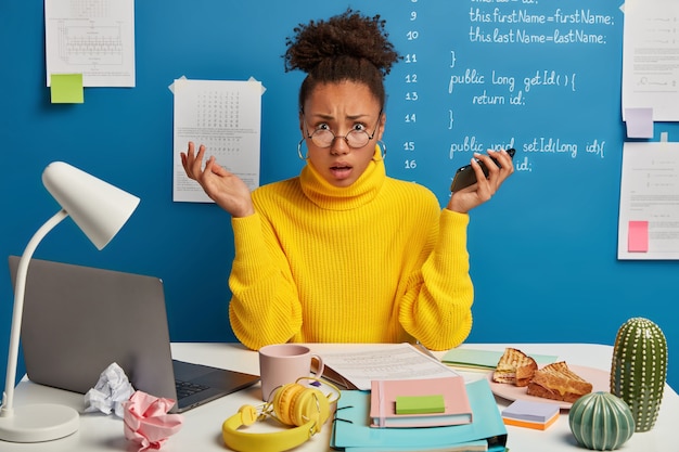 Mooie donkerbruine vrouw die op haar werkplaats verblijft