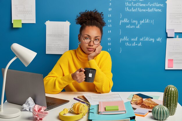 Mooie donkerbruine vrouw die op haar werkplaats verblijft