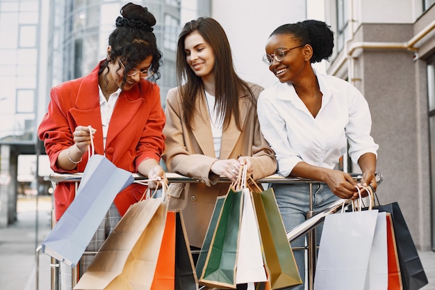 Mooie drie jonge vrouwen met een cadeauzakje lopen door de stad