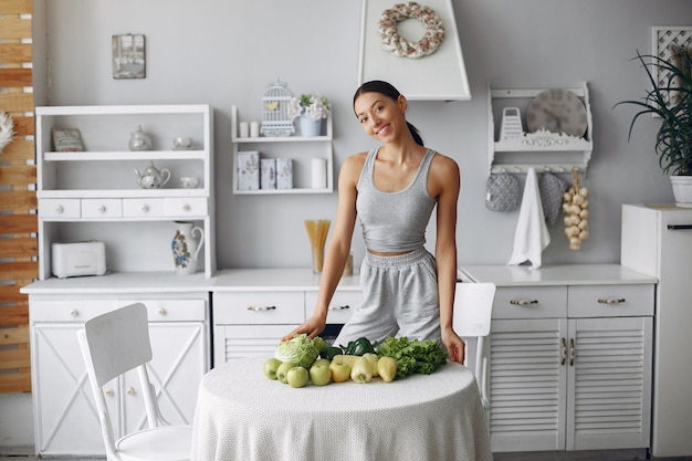 Mooie en sportieve vrouw in een keuken met groenten