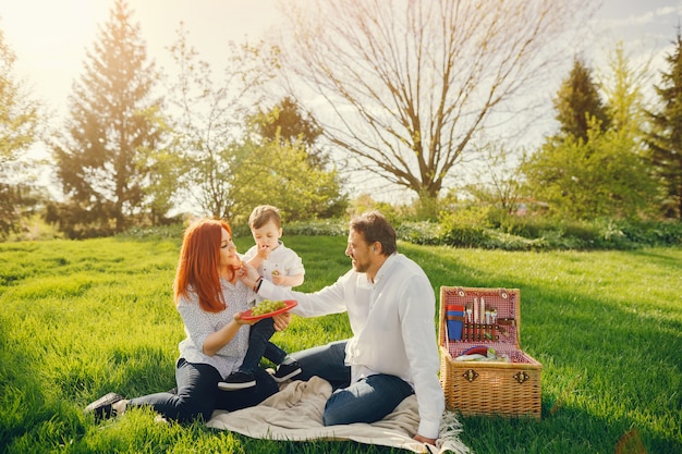 mooie en stijlvolle roodharige moeder in een witte blouse zit op het gras met haar mooie man