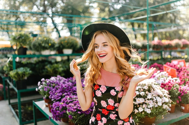 Mooie Europese vrouw die van goede dag geniet. Blij blinde vrouw met plezier op de oranjerie met bloemen.