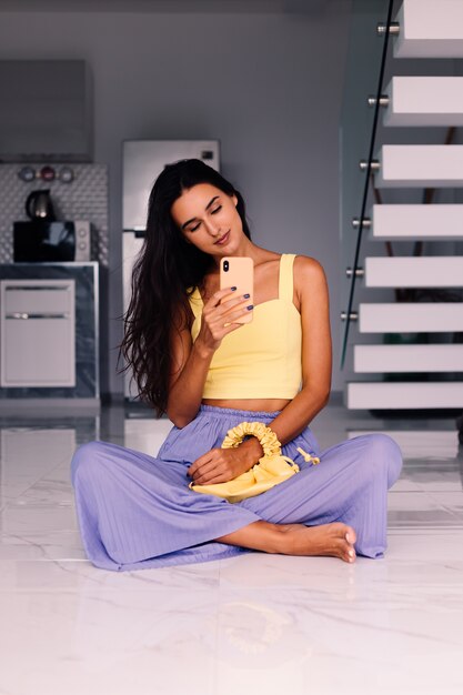 mooie fashion blogger vrouw met gele top en paarse broek