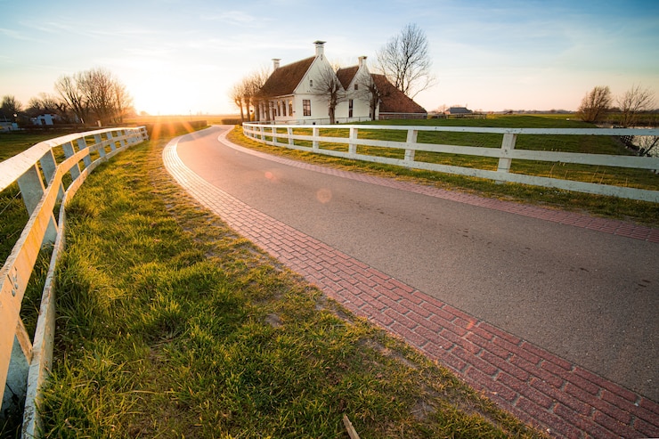 Gratis Foto mooie foto van een weg met witte hekken naast het huis bij zonsondergang