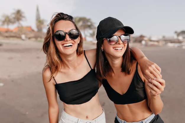 Mooie gelukkig lachend vriendinnen genieten van een wandeling op het strand op een zonnige dag Twee jonge vrouwen lopen samen op een strand en genieten van vakantie