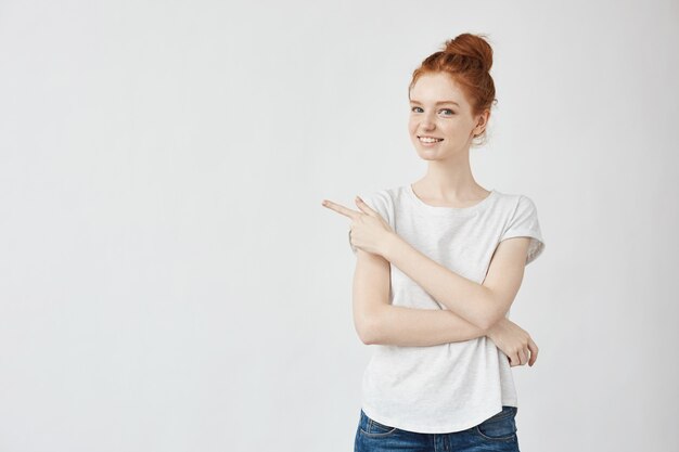 Mooie gembervrouw die wijzend vinger in kant glimlachen.