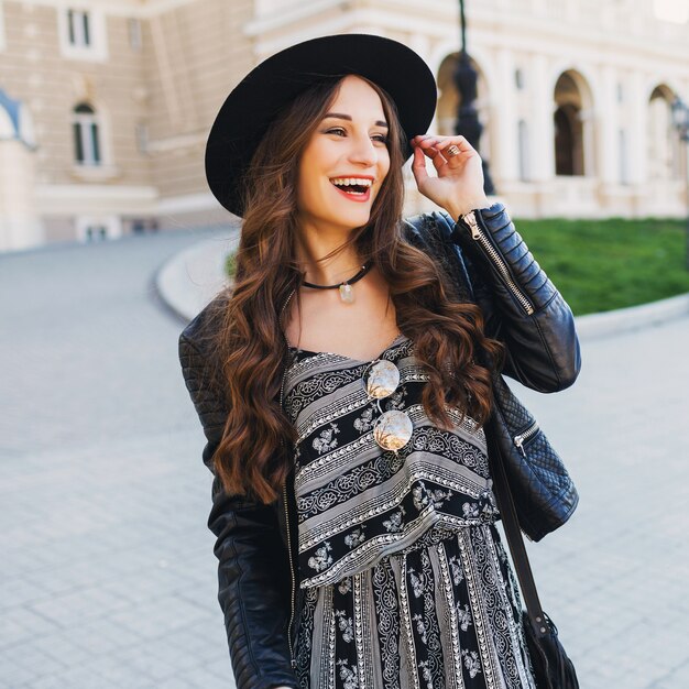 Mooie geweldige brunette vrouw met lang golvend kapsel in de lente of herfst stijlvolle stedelijke outfit lopen op straat. Rode lippen, slank lichaam. Street fashion concept.