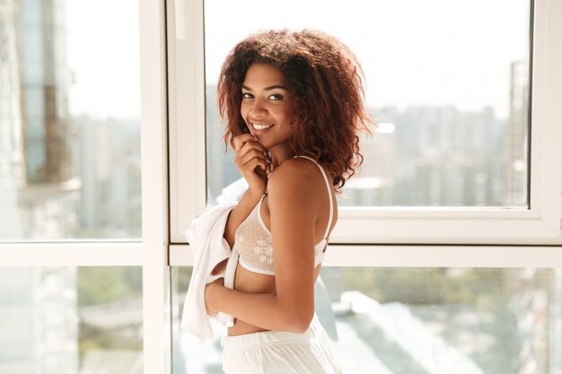 Mooie glimlachende afro Amerikaanse vrouw in lingerie het stellen