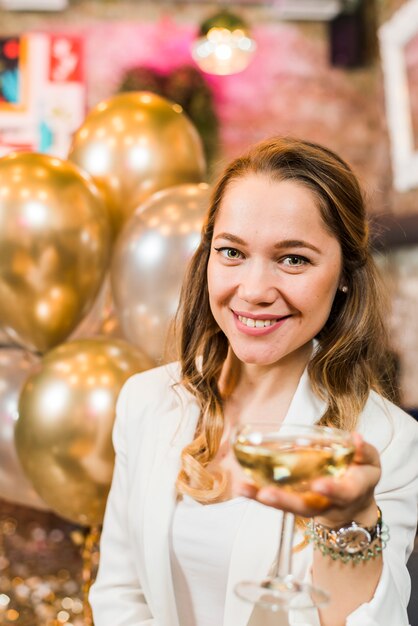 Mooie glimlachende vrouw die een glas whisky aanbiedt