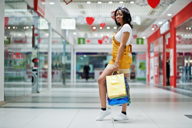 Mooie goed geklede afro-amerikaanse vrouw klant met gekleurde boodschappentassen in winkelcentrum