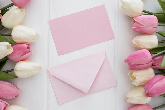 Mooie groetkaart en envelop met bloemen van tulpen op witte houten achtergrond