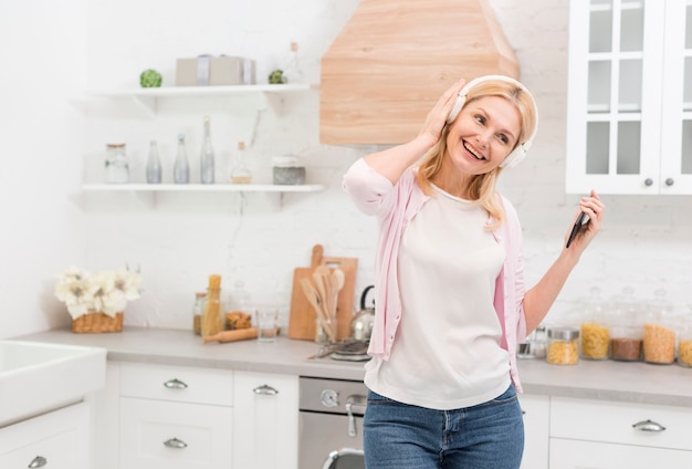 Mooie hogere vrouw die aan muziek luistert