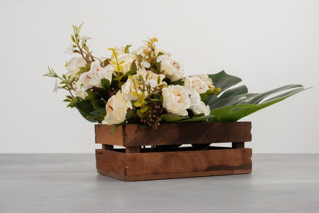 Mooie houten kist met witte rozen op grijze ondergrond