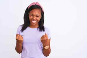 Gratis foto mooie jonge afro-amerikaanse vrouw draagt een diadeem over geïsoleerde achtergrond erg blij en opgewonden doet winnaargebaar met opgeheven armen glimlachend en schreeuwend voor succes viering concept