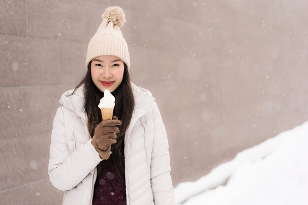 Mooie jonge Aziatische vrouwenglimlach en gelukkig met roomijs in sneeuw wintertijd