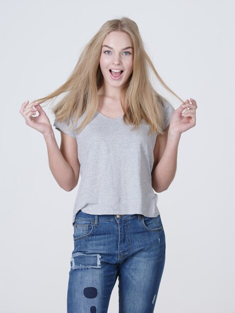 Gratis foto mooie jonge lachende blanke vrouw met lang blond haar poseren op een witte achtergrond.