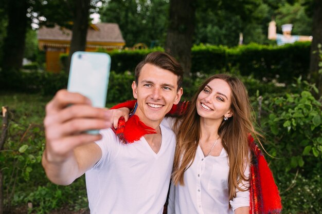 Mooie jonge paar ontspannen in het park en maakt selfie