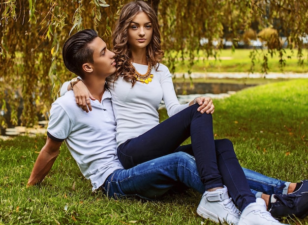 Gratis foto mooie jonge paar ontspannen op grasveld in een park.