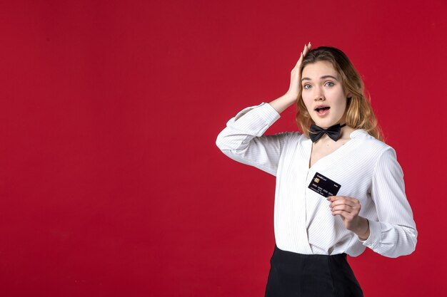 mooie jonge verraste vrouwelijke servervlinder in de nek en met bankkaart op rode achtergrond