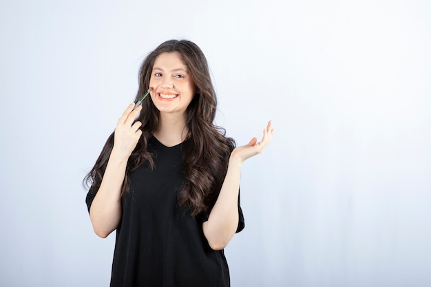 Mooie jonge vrouw blozen met cosmetische borstel over witte muur.