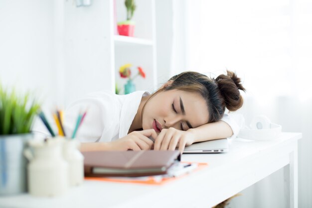 Mooie jonge vrouw die aan haar laptop in haar ruimte werkt.