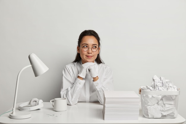 Mooie jonge vrouw die bij haar bureau bestudeert