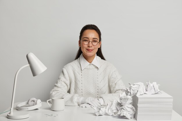 Mooie jonge vrouw die bij haar bureau bestudeert