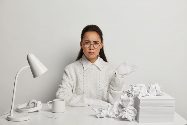 Mooie jonge vrouw die bij haar bureau bestudeert