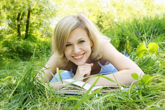 Mooie jonge vrouw die een boek leest over de natuur Premium Foto