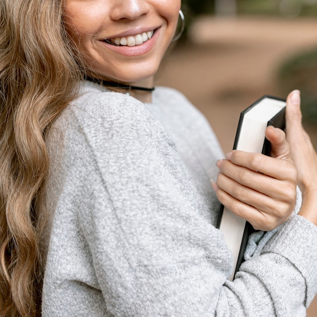 Gratis foto mooie jonge vrouw die een boekclose-up houdt