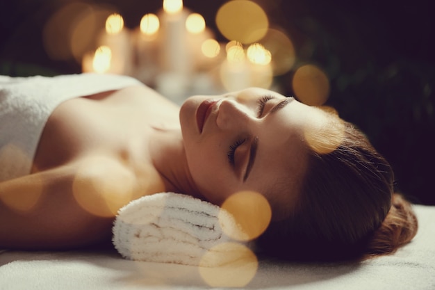 Mooie jonge vrouw die en op haar massage ligt te wachten. Spa concept