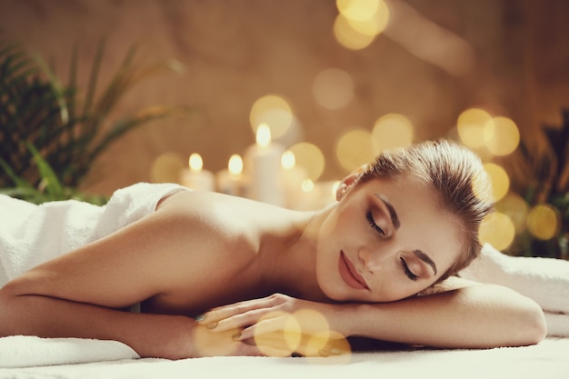 Gratis foto mooie jonge vrouw die en op haar massage ligt te wachten. spa concept