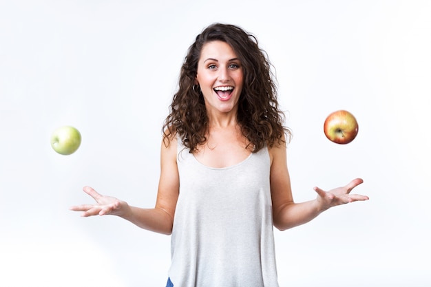 Mooie jonge vrouw die groene en rode appels op witte achtergrond houdt.