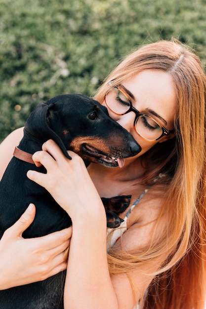 Gratis foto mooie jonge vrouw die haar hond kust