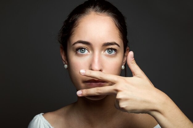 Mooie jonge vrouw die haar mond met de hand bedekt. Geïsoleerd.