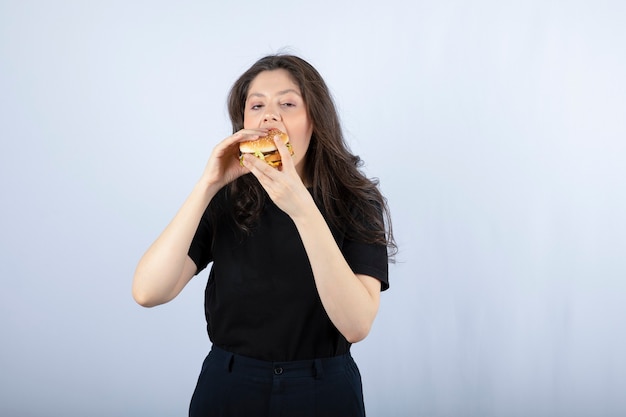 Mooie jonge vrouw die heerlijke rundvleeshamburger eet.