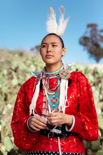 Mooie jonge vrouw die inheems amerikaans kostuum draagt