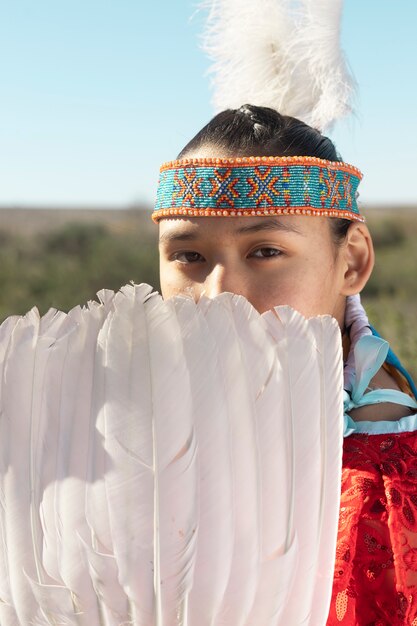 Mooie jonge vrouw die inheems Amerikaans kostuum draagt