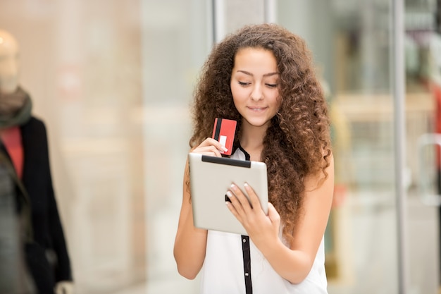 Mooie jonge vrouw die met creditcard betaalt om te winkelen