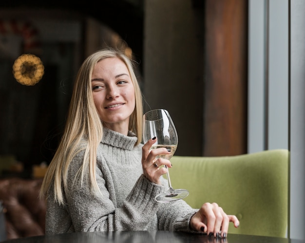 Mooie jonge vrouw die met glas wijn weg kijkt