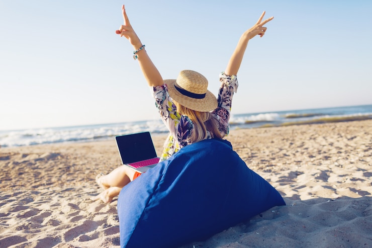 Gratis Foto mooie jonge vrouw die met laptop aan het tropische strand werkt