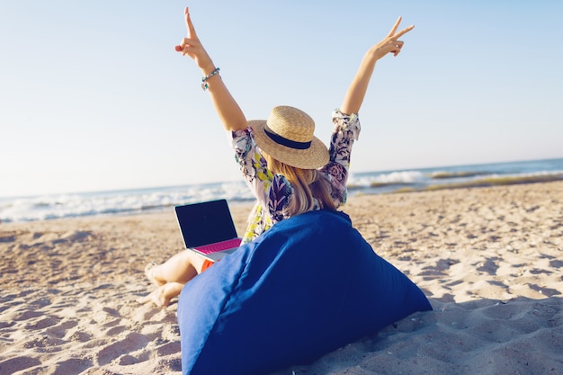 Mooie jonge vrouw die met laptop aan het tropische strand werkt