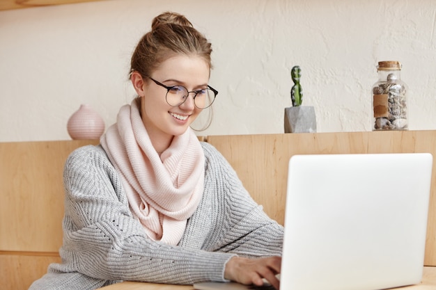 Mooie jonge vrouw die met laptop werkt