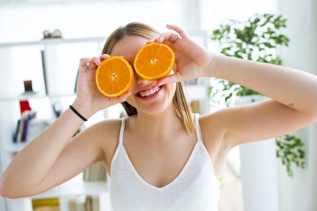 Mooie jonge vrouw die met oranje vruchten speelt.