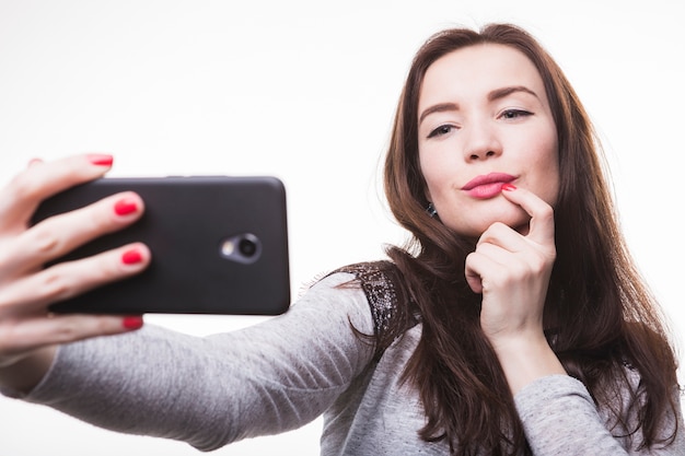 Mooie jonge vrouw die selfie door cellphone neemt