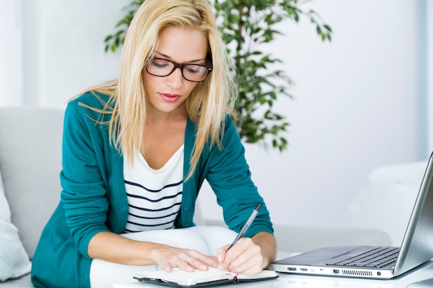 Gratis foto mooie jonge vrouw die thuis met laptop werkt.